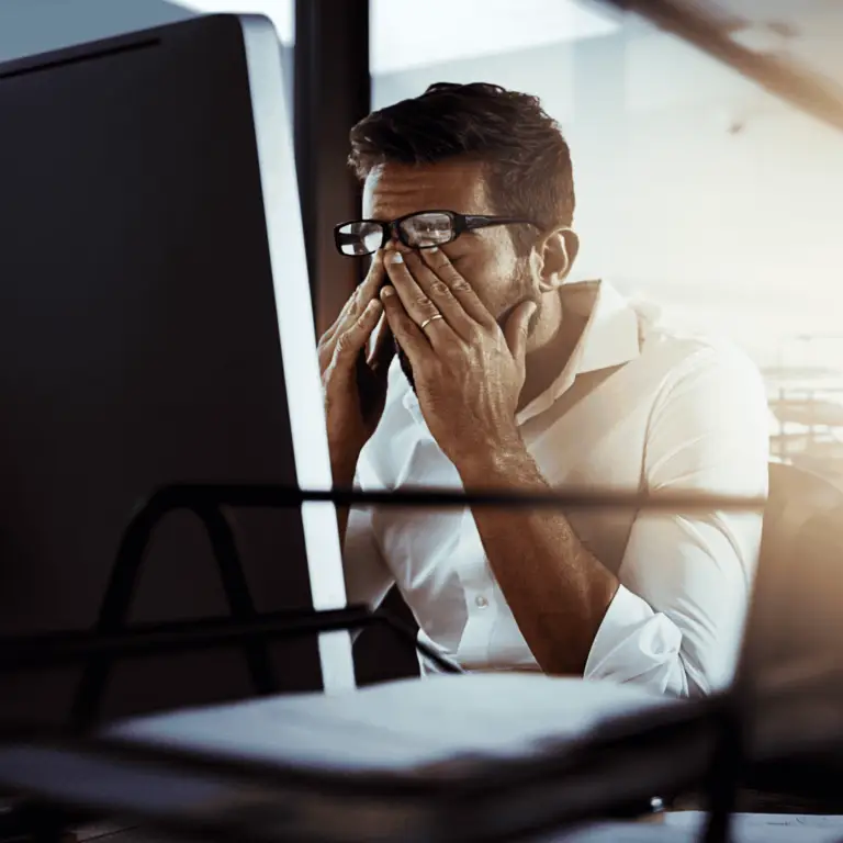 Frustrated businessman at his desk looking overwhelmed by technology issues, symbolizing that you've outgrown your IT provider.