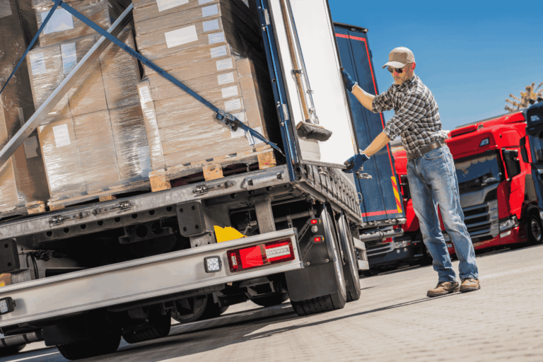 Workers loading finished goods onto a truck at a manufacturing facility — minimizing manufacturing downtime through efficient logistics.