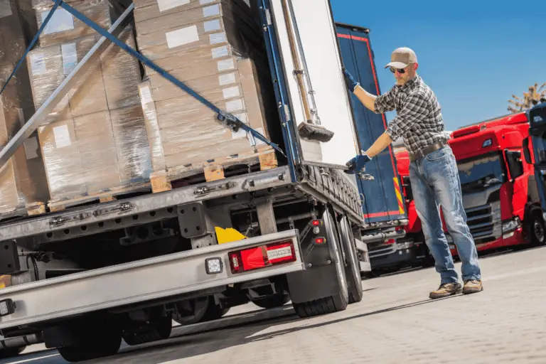 Workers loading finished goods onto a truck at a manufacturing facility — minimizing manufacturing downtime through efficient logistics.