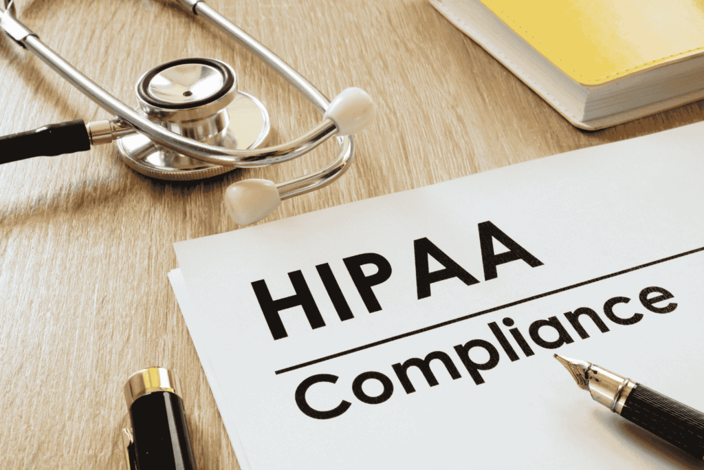 Doctor’s desk with a clipboard and stethescope displaying “HIPAA Compliance” text, representing the importance of a HIPAA risk assessment.