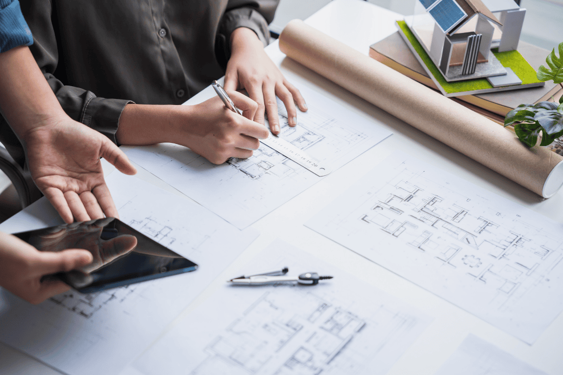 Architectural professional collaborating on digital plans with IT support for small business.