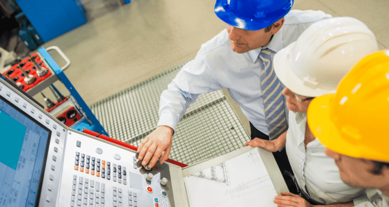 Three executives inspecting machinery on a factory floor, representing strategic manufacturing and operational oversight