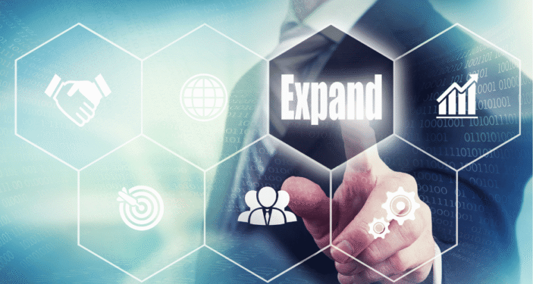 Finger pointing to the word "Expand" with digital technology icons representing Managed IT Services for Multiple Manufacturing Locations