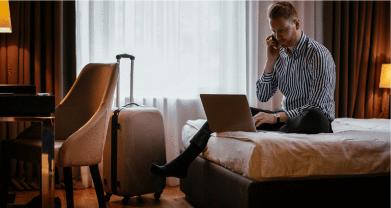 Guest using multiple connected devices in a hotel room, illustrating how Redundant Infrastructure for Hotels supports reliable Wi-Fi, business continuity, and a seamless guest experience