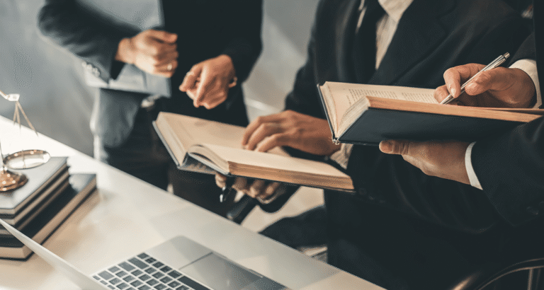 Attorney working efficiently with digital case files on a laptop while collaborating in a modern law office.
