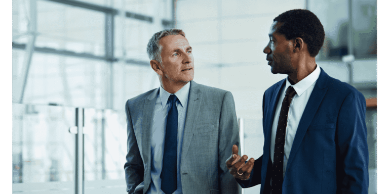 Two business professionals discussing technology solutions in a busy hotel lobby, representing Vendor Liaison services for hotels.